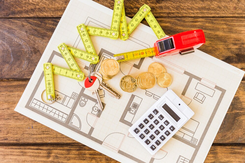 Construction plan, coins, keys and calculator on table