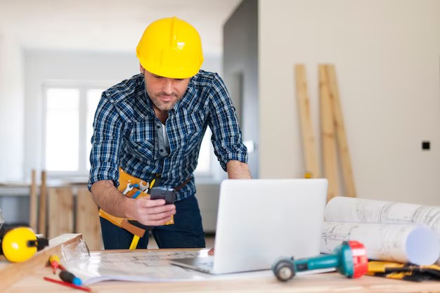 Contractor working on phone with laptop