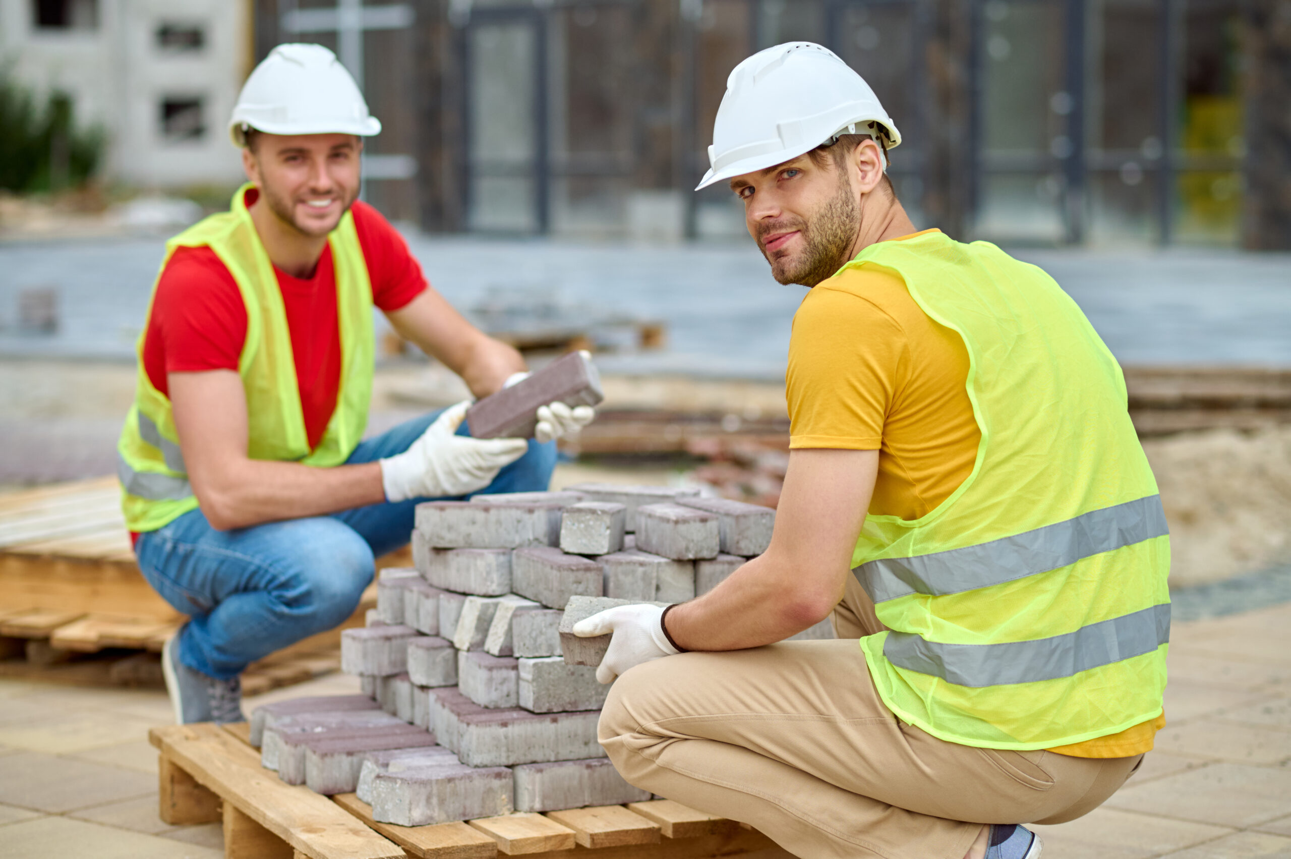 Two workers stacking bricks looking at camera